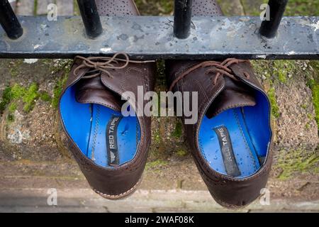 Une paire de chaussures brunes lacées et jetées sont épinglées sous les balustrades dans une rue à Loughborough Junction, le 3 janvier 2024, à Londres, en Angleterre. Banque D'Images