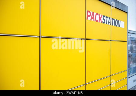 Innovative Paketlogistik - Nutzung der DHL Packstation 04.01.2024, Bad Camberg : Symbolfoto, Illustrationsbild, Symbolbild, Illustrationsfoto Das Bild zeigt eine Frau im Anschnitt, die mit ihrem smartphone über den Touchscreen einer DHL Paketstation interagiert, UM ein Paket einzureichen. SIE ist konzentriert auf die digitale Schnittstelle fokussiert, während ihre hand das Mobiltelefon hält und die entsprechenden Eingaben auf dem Bildschirm der Paketstation tätigt UM das Paket einzulegen. Die Packstation, ein Paketautomatensystem von DHL, bietet seit 2001 in über 12,500 Standorten deutschlandwe Banque D'Images