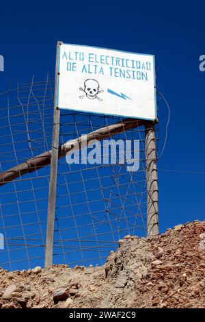 Peligro / signe de danger en espagnol avertissement de câbles électriques à haute tension sur le barrage de résidus miniers des mines voisines à la périphérie de Potosi, Bolivie Banque D'Images