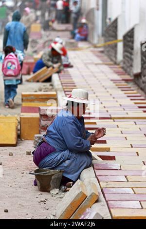 Femmes quechua locales travaillant sur un projet de travaux publics posant un nouveau trottoir / trottoir en briques, Potosi, Bolivie Banque D'Images