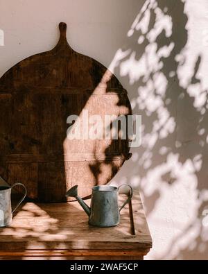 Une planche en bois de style vintage et un arrosoir en métal sur une table rustique dans le jardin Banque D'Images