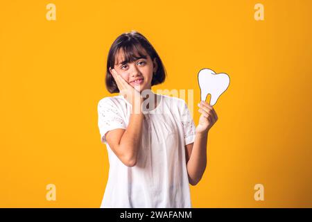 Enfant fille tenant la dent de papercraft et sentir mal aux dents. Concept de santé dentaire Banque D'Images