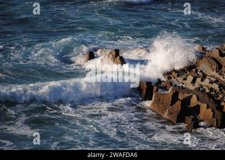 Panorama depuis le haut de la côte au-dessus de la plage de Sopelana près de Bilbao, Espagne. Détail des vagues qui s'écrasent sur les rochers générant de la mousse blanche. Banque D'Images