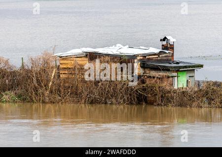 04 janvier 2024, Hesse, Gießen : le Lahn a fait éclater ses banques. Un abri de jardin sur les prairies et les champs sur la rive ouest de la rivière est entouré par les eaux de crue. Photo : Christian Lademann/dpa Banque D'Images