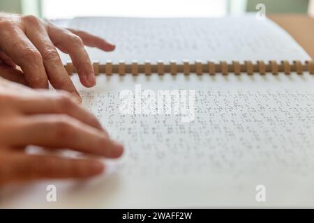 Personne aveugle ou malvoyante lisant un livre imprimé avec des caractères braille. Banque D'Images