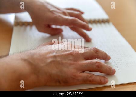 Personne aveugle ou malvoyante lisant un livre imprimé avec des caractères braille. Banque D'Images