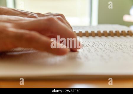 Personne aveugle ou malvoyante lisant un livre imprimé avec des caractères braille. Banque D'Images