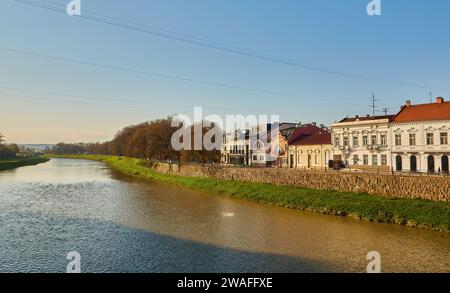 rive de la rivière uzh. magnifique paysage urbain en été. vue de dessous l'ombre d'un arbre de linden branches. pont au loin Banque D'Images