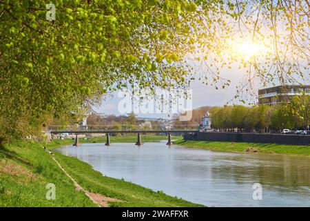 rive de la rivière uzh. magnifique paysage urbain en été. vue de dessous l'ombre d'un arbre de linden branches. pont au loin Banque D'Images