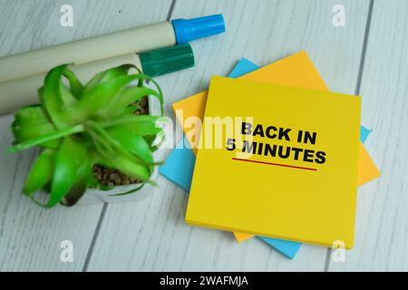 Concept de Retour en 5 minutes écrire sur des notes autocollantes isolées sur la table en bois. Banque D'Images