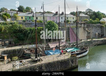 Un couple se tient debout et admirez le grand voilier amarré dans le port de Charlestown, Cornouailles, Angleterre Banque D'Images