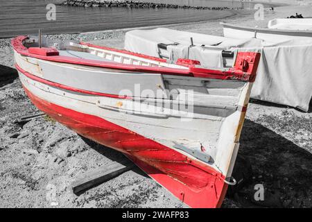 Prise de vue en noir et blanc avec couleur rouge d'un bateau de pêche espagnol rouge et blanc sur la plage de Puerto Banus, Marbella ; Costa Del sol, Espagne Banque D'Images