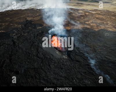 Environnement apocalyptique d'un volcan en éruption, lave rouge bouillant et déversant le cratère, gaz volcaniques et fumée se propageant autour de la zone Banque D'Images