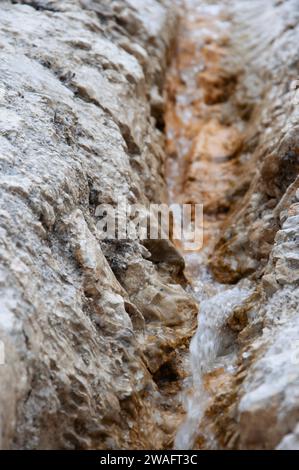 Petit ruisseau coule entre les roches calcaires ferrugineuses brunes. Flou de mouvement. Profondeur de champ étroite. Image d'arrière-plan Banque D'Images