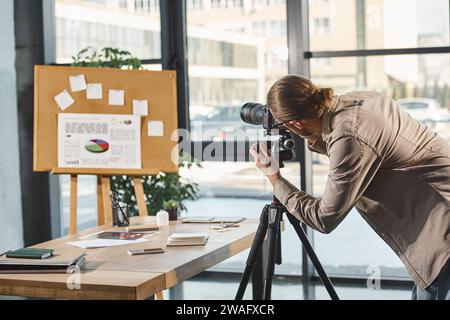 directeur créatif ajustant l'appareil photo numérique près du panneau de liège avec des graphiques pour la présentation dans le bureau Banque D'Images