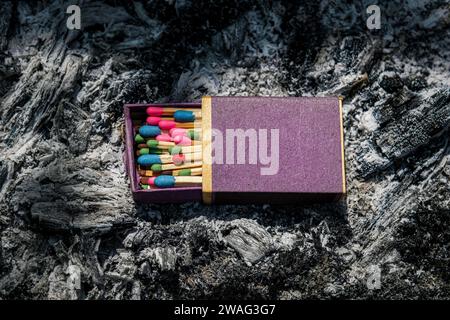 boîte ouverte d'allumettes multicolores sur les cendres d'un feu Banque D'Images