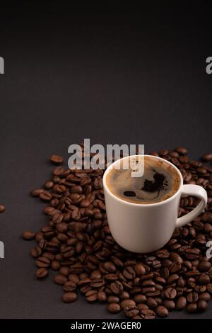 photo présente une tasse d'espresso entouré de grains de café aromatiques, créant un fond riche. Avec un grand espace de copie, c'est un complément idéal à un c Banque D'Images