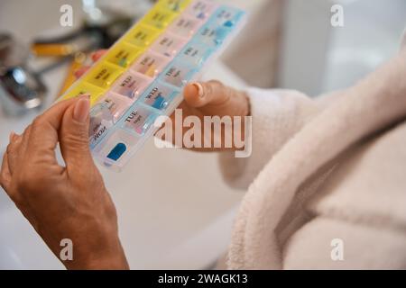Femme tient une boîte à pilules avec des cellules multicolores dans ses mains Banque D'Images