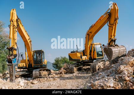 Deux excavatrices jaunes sur le chantier de construction avec terrain rocheux Banque D'Images