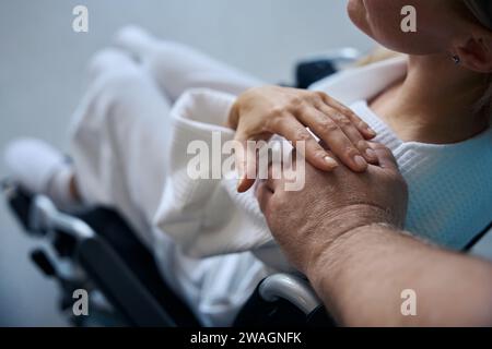 Travailleur de la santé réconfortant une femme handicapée assise dans une chaise roulante Banque D'Images