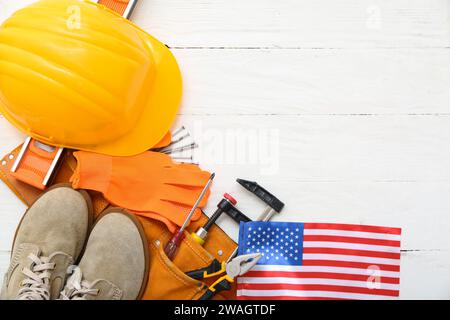 Équipement de protection, ceinture avec outils et drapeau américain sur fond en bois blanc. Célébration de la fête du travail Banque D'Images