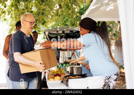Groupe de bénévoles distribuant des aliments emballés aux personnes dans le besoin, y compris les sans-abri et les personnes âgées. Leur véritable acte de charité apporte bonheur et soulagement aux moins fortunés. Banque D'Images