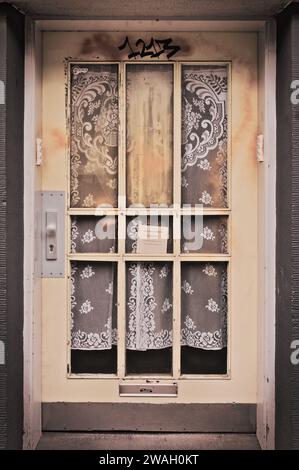 Plan vertical d'une vieille porte d'entrée brûlée à Essen, en Allemagne, avec d'élégants rideaux visibles derrière elle Banque D'Images