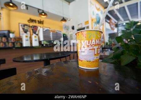 HO CHI MINH VILLE, VIETNAM - 26 MARS 2023 : gros plan d'une tasse en papier avec du café glacé servi sur une table au ONG Bau Coffee à Ho Chi Minh ville. Banque D'Images