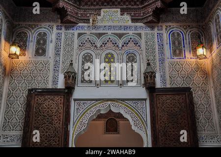 Stuc coloré complexe et portes en bois sculpté dans le patio du musée Dar Jamai, Meknès, Maroc. Banque D'Images