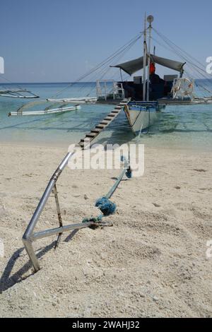 Un bateau traditionnel philippin ou Outrigger est amarré à l'île de Kalanggaman par une belle journée claire et ancré sur une plage de sable. Banque D'Images