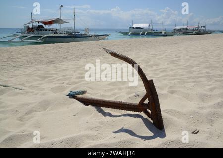 Un bateau traditionnel philippin ou Outrigger est amarré à l'île de Kalanggaman par une belle journée claire et ancré sur une plage de sable. Banque D'Images