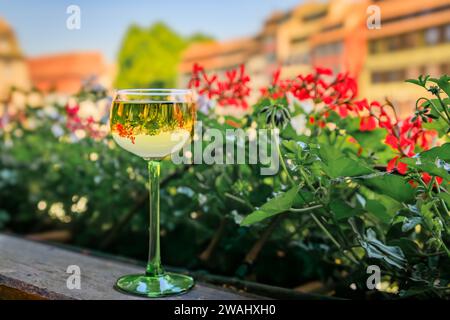 Un verre de vin Gewurztraminer dans un restaurant en plein air, maisons à colombages floues et fleurs dans le quartier de la petite France à Strasbourg, France Banque D'Images