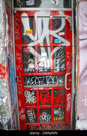 Une porte rouge vibrante avec des graffitis couvrant la surface à New York, aux États-Unis Banque D'Images