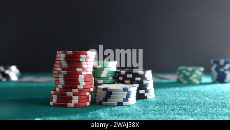 Détail des piles de jetons de pari de différentes couleurs sur tapis de jeu vert avec fond isolé foncé. Vue avant. Banque D'Images