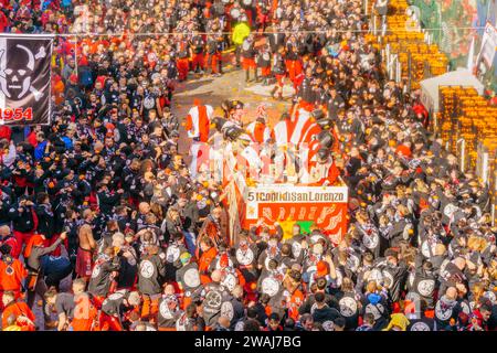 Ivrea, Italy - February 19, 2023: Groups in traditional dressings, and crowd with red hats, take part in the Battle of the Oranges, part of the histor Banque D'Images