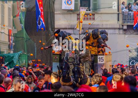 Ivrea, Italie - 19 février 2023: Des groupes de pansements traditionnels, et de la foule avec des chapeaux rouges, prennent part à la bataille des oranges, une partie de l'histor Banque D'Images