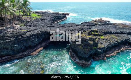 Une vue aérienne du paysage d'une falaise magnifique avec un pont entre deux affleurements rocheux, complétée par des palmiers luxuriants de chaque côté Banque D'Images