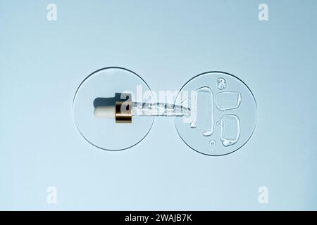 Vue de dessus de la composition minimaliste avec un compte-gouttes de sérum et du liquide renversé sur deux surfaces en verre représentant des produits de soin haut de gamme Banque D'Images