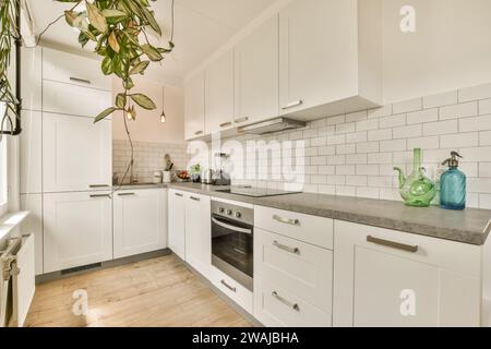 Cuisinière et mélangeur sur le comptoir de cuisine spacieuse dans un appartement moderne avec armoires blanches et radiateur Banque D'Images