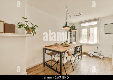 Lampes suspendues suspendues au-dessus d'une table et de chaises en bois dans la salle à manger d'un appartement luxueux avec fenêtre et armoire Banque D'Images