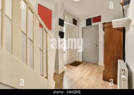 Hall d'entrée de la maison moderne avec placard en bois et escalier blanc et radiateur avec portes fermées Banque D'Images