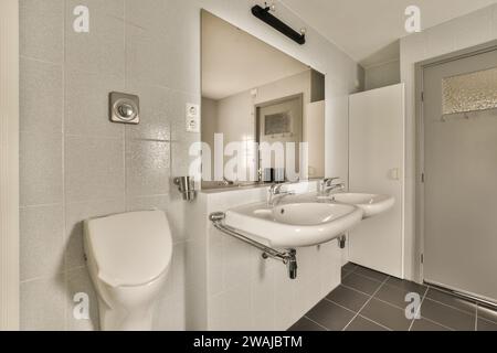 WC par deux lavabos avec miroir monté sur le mur dans la salle de bains spacieuse de l'appartement contemporain Banque D'Images