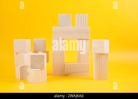 blocs de construction en bois, poutres et cubes isolés sur un fond jaune Banque D'Images