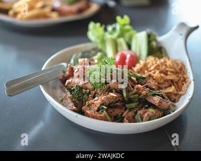 Thaï Street food. Salade de porc grillé épicé, porc grillé au charbon de bois et tranché (Moo Nam Tok). Banque D'Images