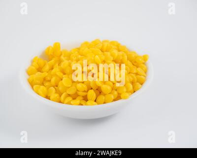 Un bol plein de peaux de cire d'abeille jaune naturel isolé sur un fond blanc Banque D'Images