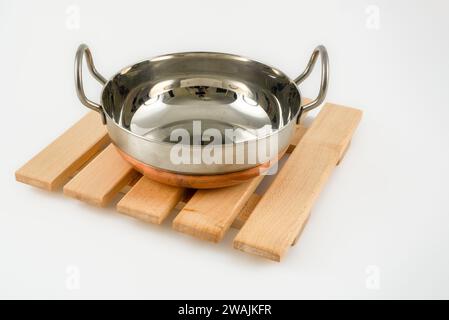 Plat en bois dur ferme avec un plat de curry indien Balti chaud à fond de cuivre isolé sur un fond blanc Banque D'Images