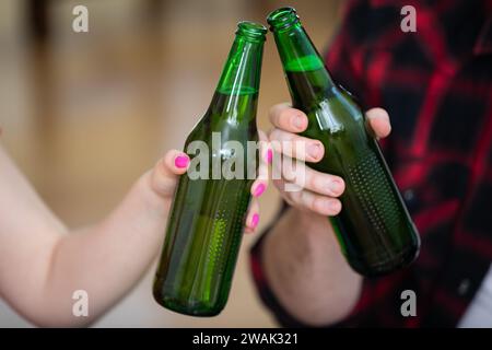 Gros plan sur deux bouteilles de bière tenues par un garçon et une fille. Banque D'Images