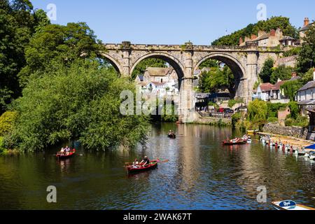 Touristes en bateaux à rames loués sur la rivière Nidd avec le viaduc ferroviaire, Pateley Bridge. Knaresborough, Yorkshire, Angleterre Banque D'Images