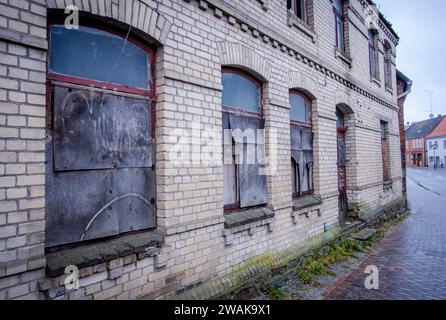 Goldberg, Allemagne. 13 décembre 2023. Fenêtres recouvertes de panneaux dans une maison vacante du centre-ville. Des bâtiments résidentiels et commerciaux vides et partiellement délabrés caractérisent l'image de la petite ville de Goldberg dans le Mecklembourg-Poméranie occidentale. Crédit : Jens Büttner/dpa/Alamy Live News Banque D'Images