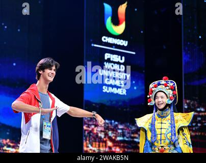 (240105) -- BEIJING, 5 janv. 2024 (Xinhua) -- Jack Matthew Dunn (à gauche), des États-Unis, imite le geste d'un artiste de l'Opéra du Sichuan lors d'une fête organisée pour les athlètes lors des 31e Jeux mondiaux universitaires d'été de la FISU à Chengdu, dans la province du Sichuan, dans le sud-ouest de la Chine, le 29 juillet 2023. (Xinhua/Zhang Duan) Banque D'Images